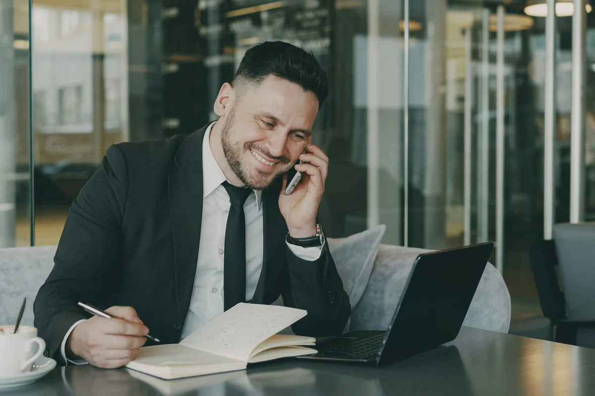 Conseiller au téléphone devant un ordinateur portable et un carnet de notes