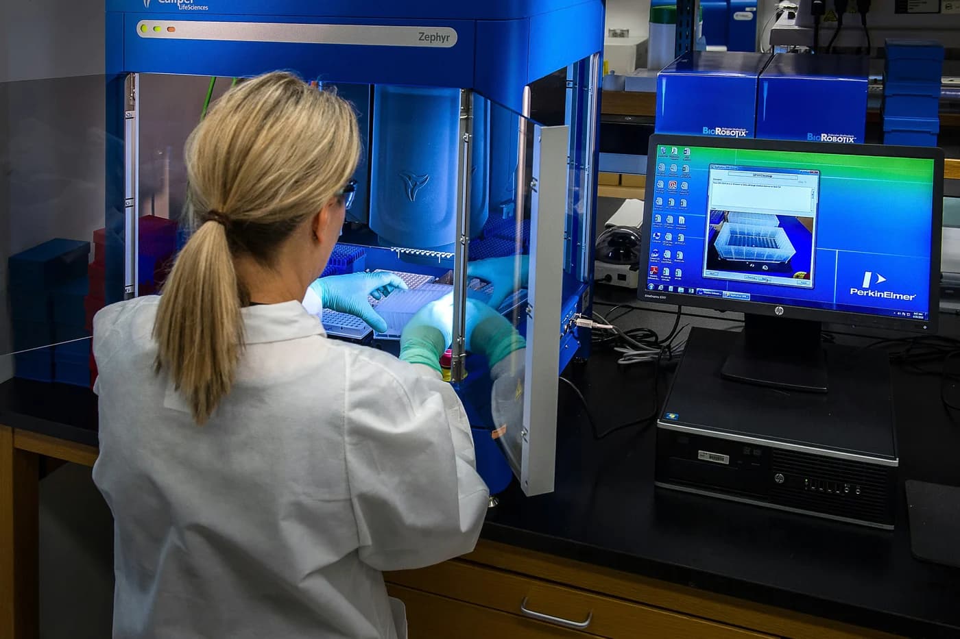 A lab technician at an automated sample preparation station